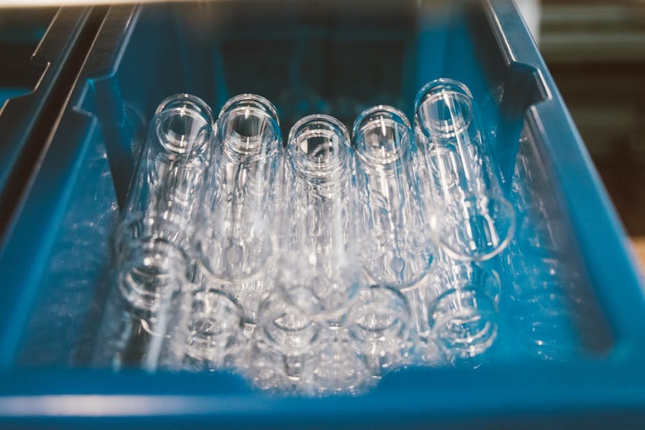 A collection of empty glass test tubes stored in a blue laboratory tray under bright lighting.
